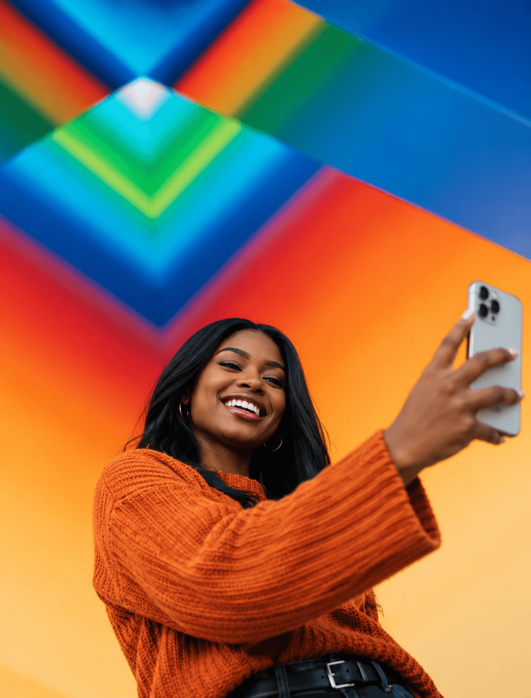 A creator laughing as she takes a selfie in front of a colourful mural
